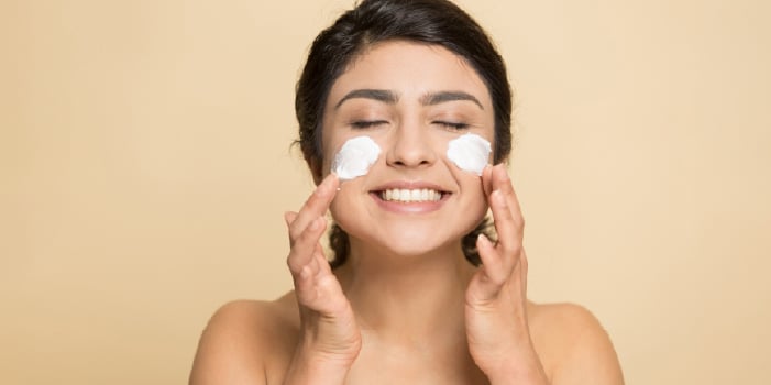 A woman with skin care on her face smiling