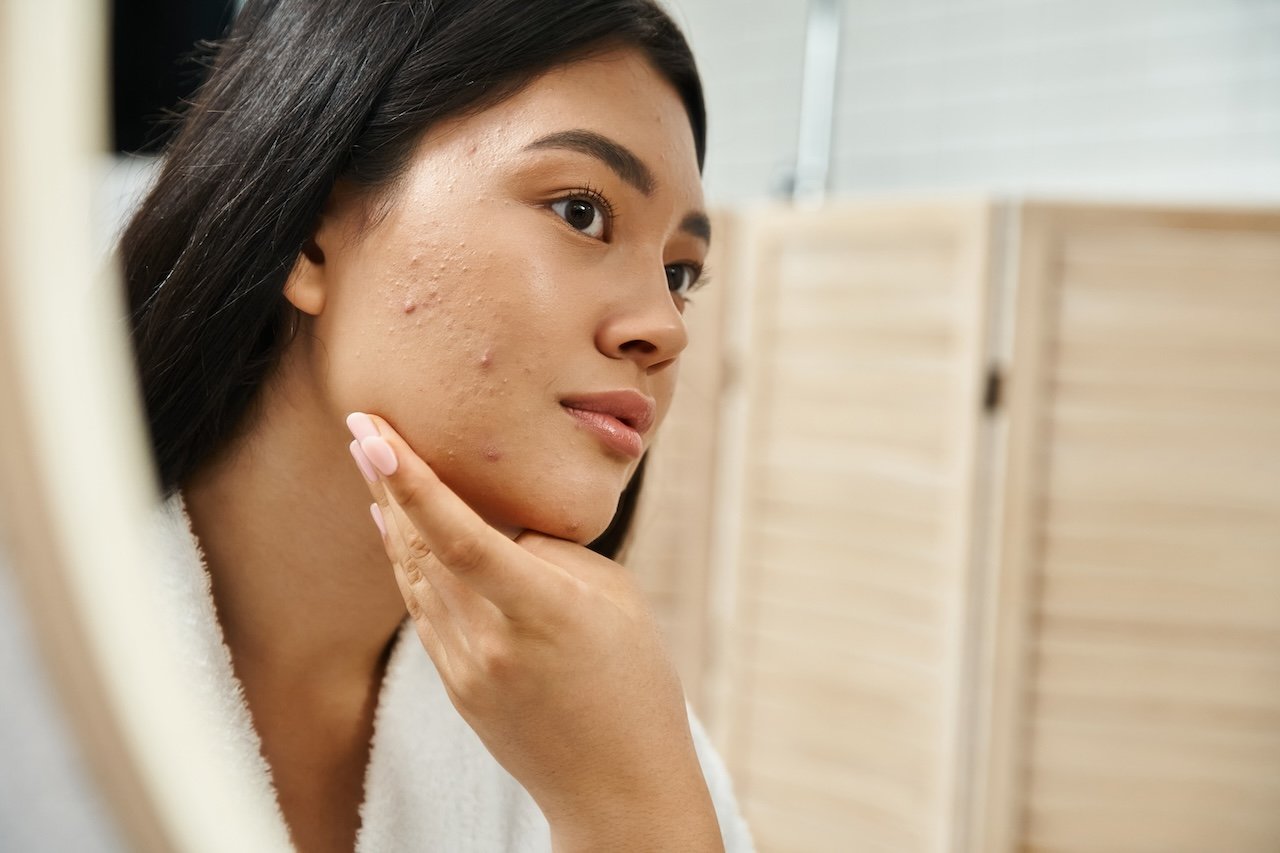 woman checking acne and skin texture in the mirror