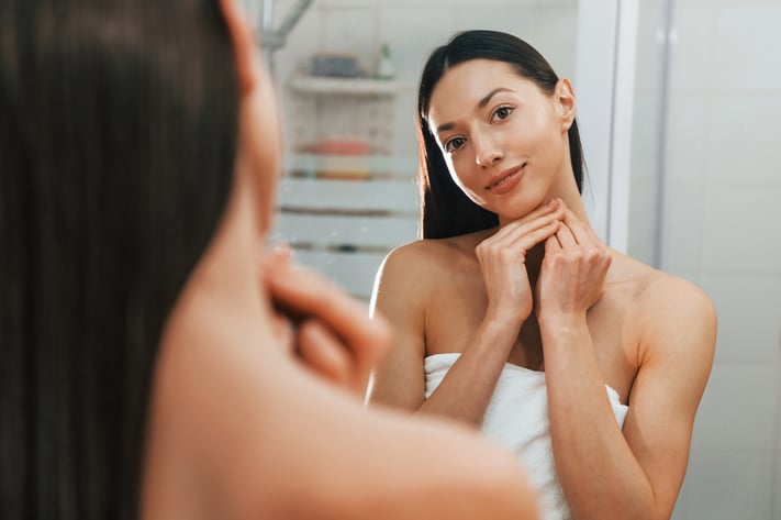 woman with healthy skin looking in the mirror
