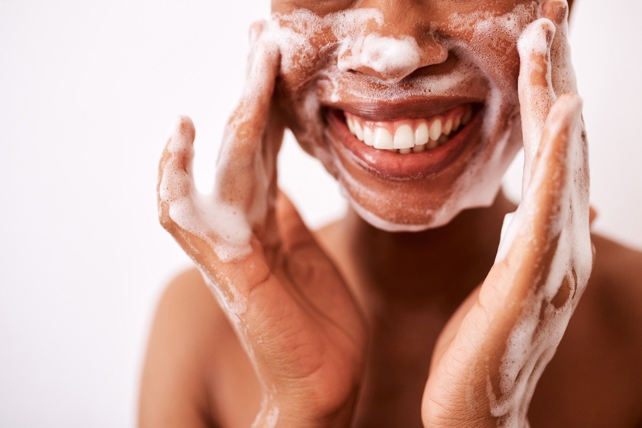 woman washing face with postpartum skincare