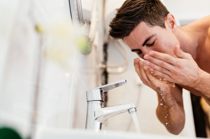 Man washing his face using a new daily skincare routine