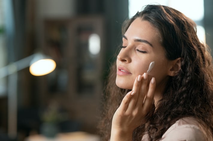 woman applying moisturizer during a postpartum skincare routine