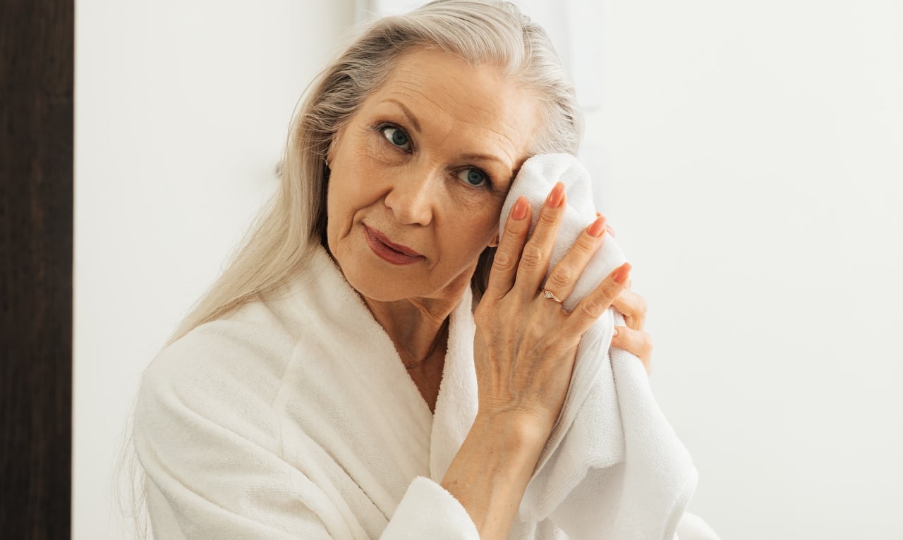 mature woman using towel to dry face after using cbd skincare