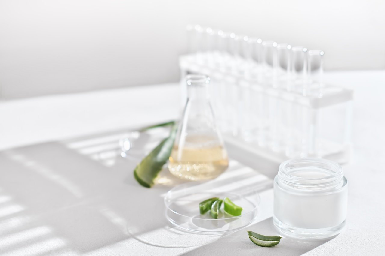 aloe vera leaves, skincare cream, and laboratory glassware