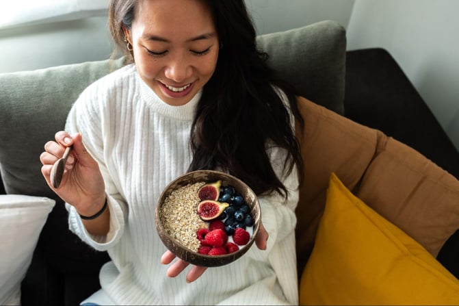 woman eating a healthy breakfast with gut friendly foods to support gut health and overall skin wellness
