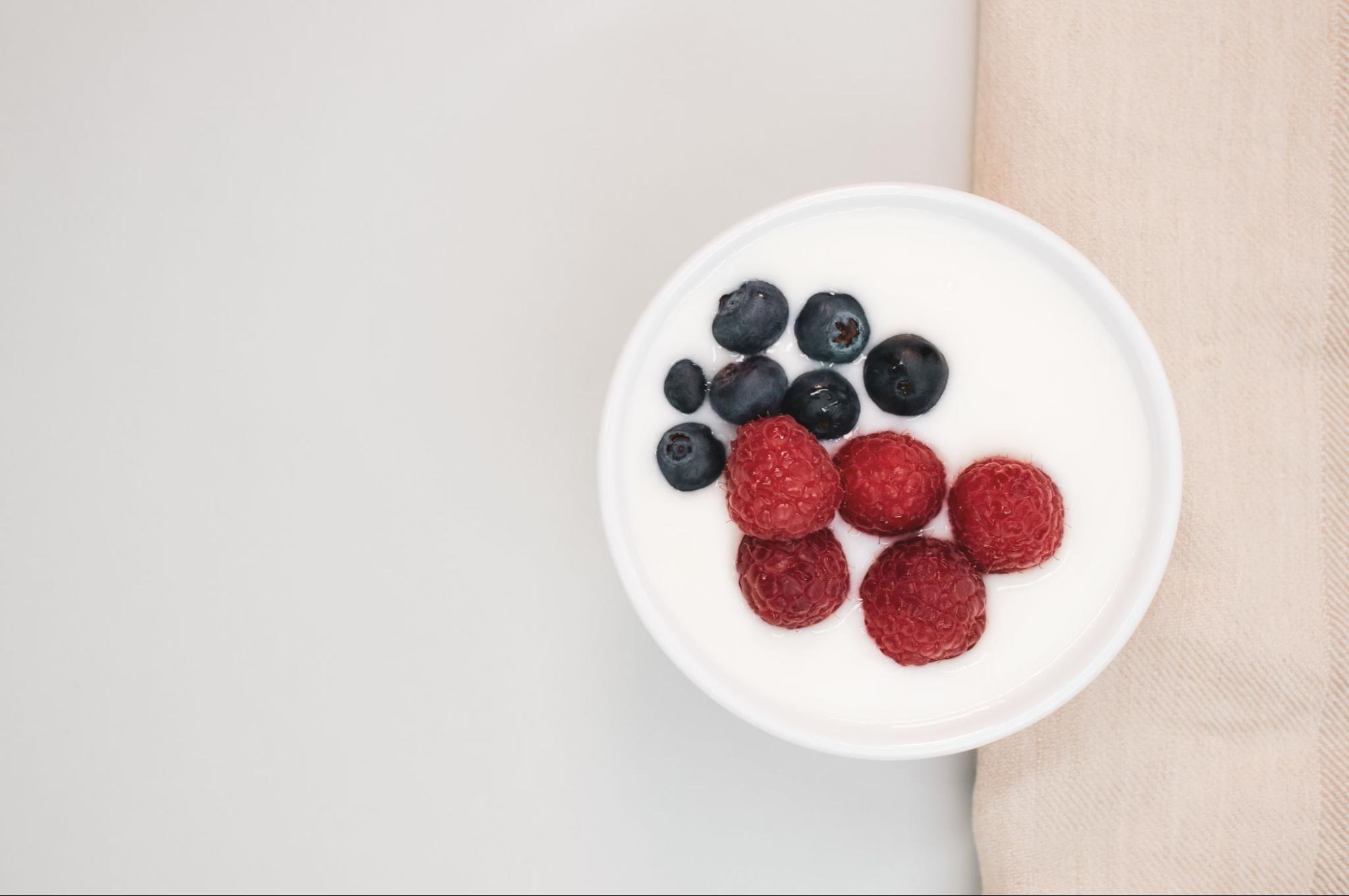 yogurt with blueberries and raspberries as a gut-friendly snack for healthy skin.