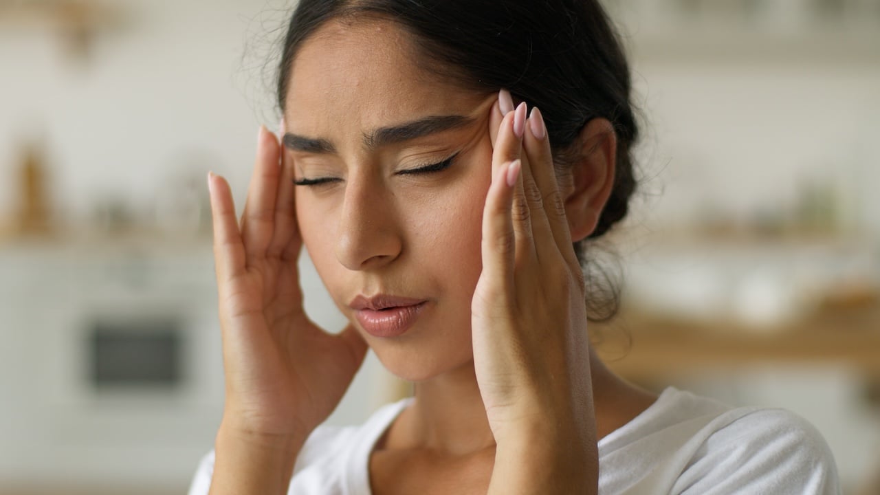 woman holding her temples while experiencing stress